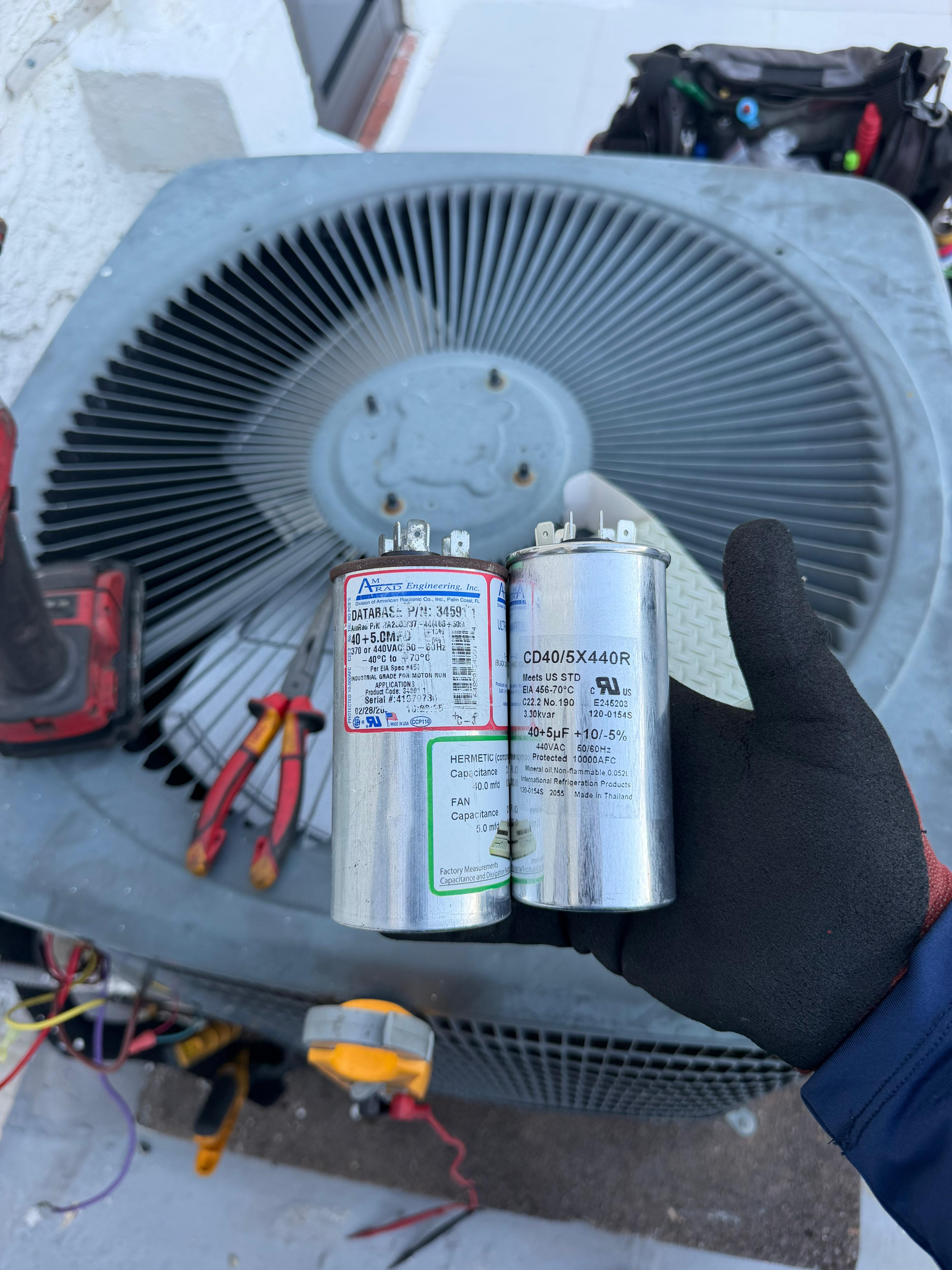 Side-by-side capacitor comparison — failed vs new replacement capacitor
