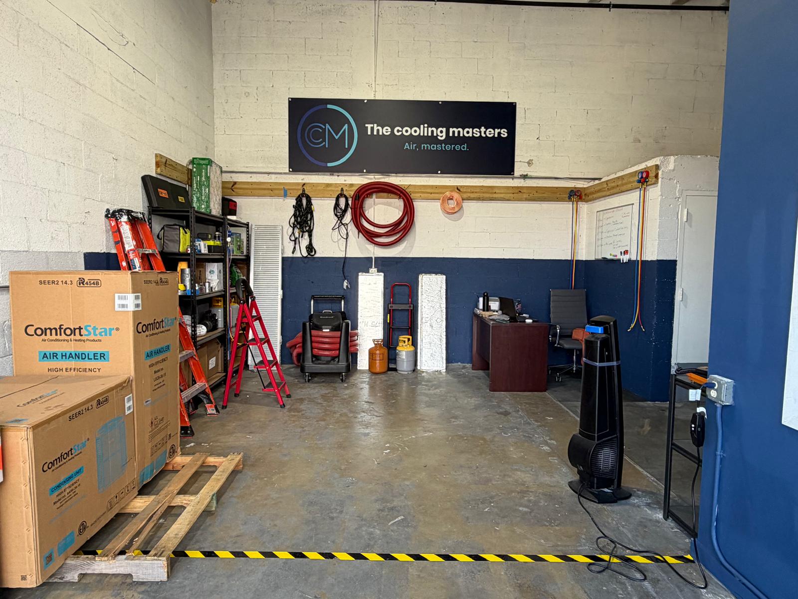 Cooling Masters warehouse interior with The Cooling Masters Air Mastered banner and equipment